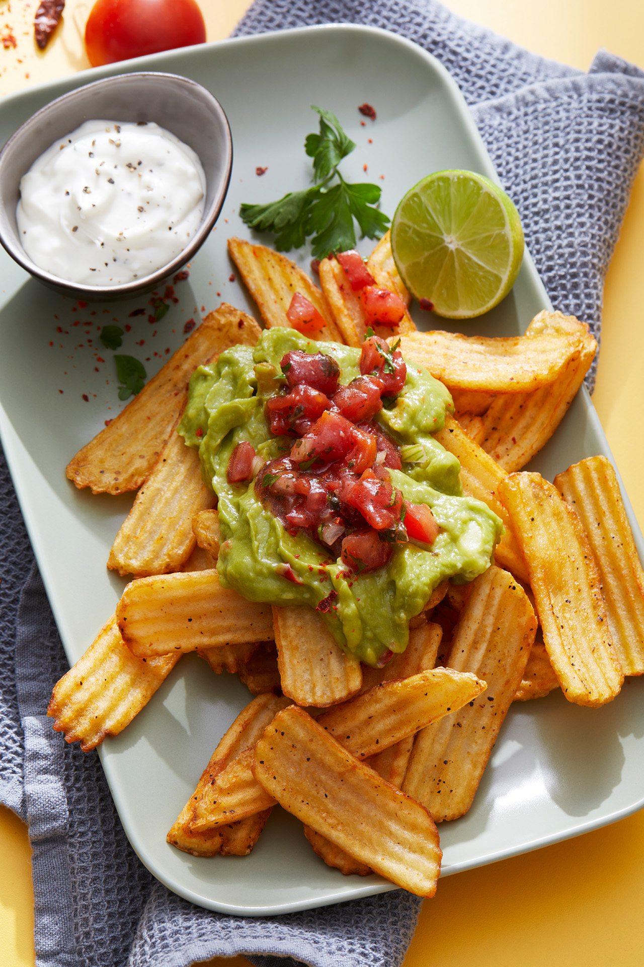 Black Pepper Waves mit Guacamole und Tomatensalsa, serviert mit Limette und Dip auf einem Teller.
